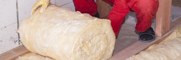 person rolling out insulation in attic