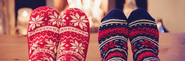 two people with holiday socks on in front of a fireplace